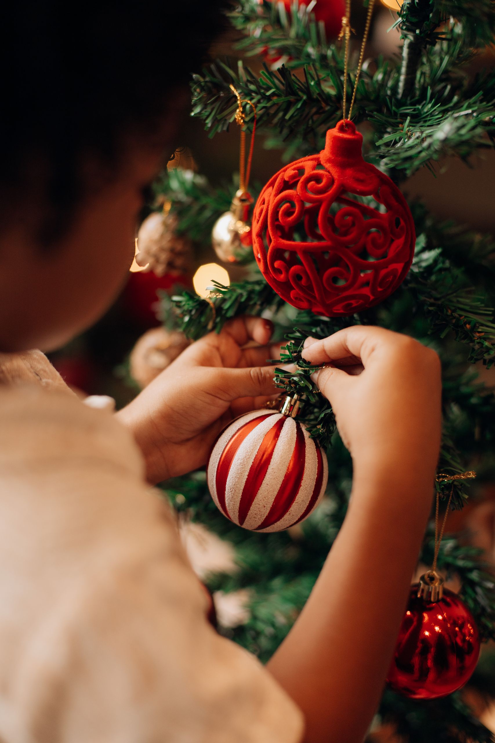 A child places ornaments on a Christmas tree, creating a festive holiday atmosphere.