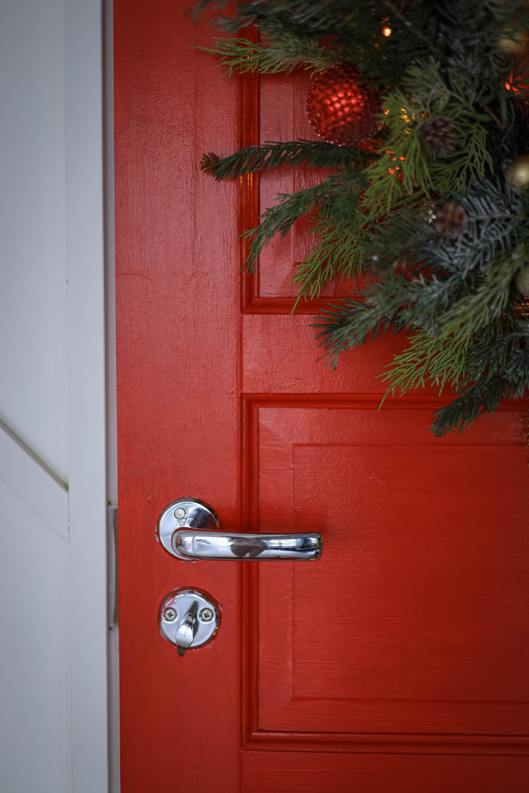 A close-up of a red door adorned with Christmas wreath, perfect for festive decoration themes.