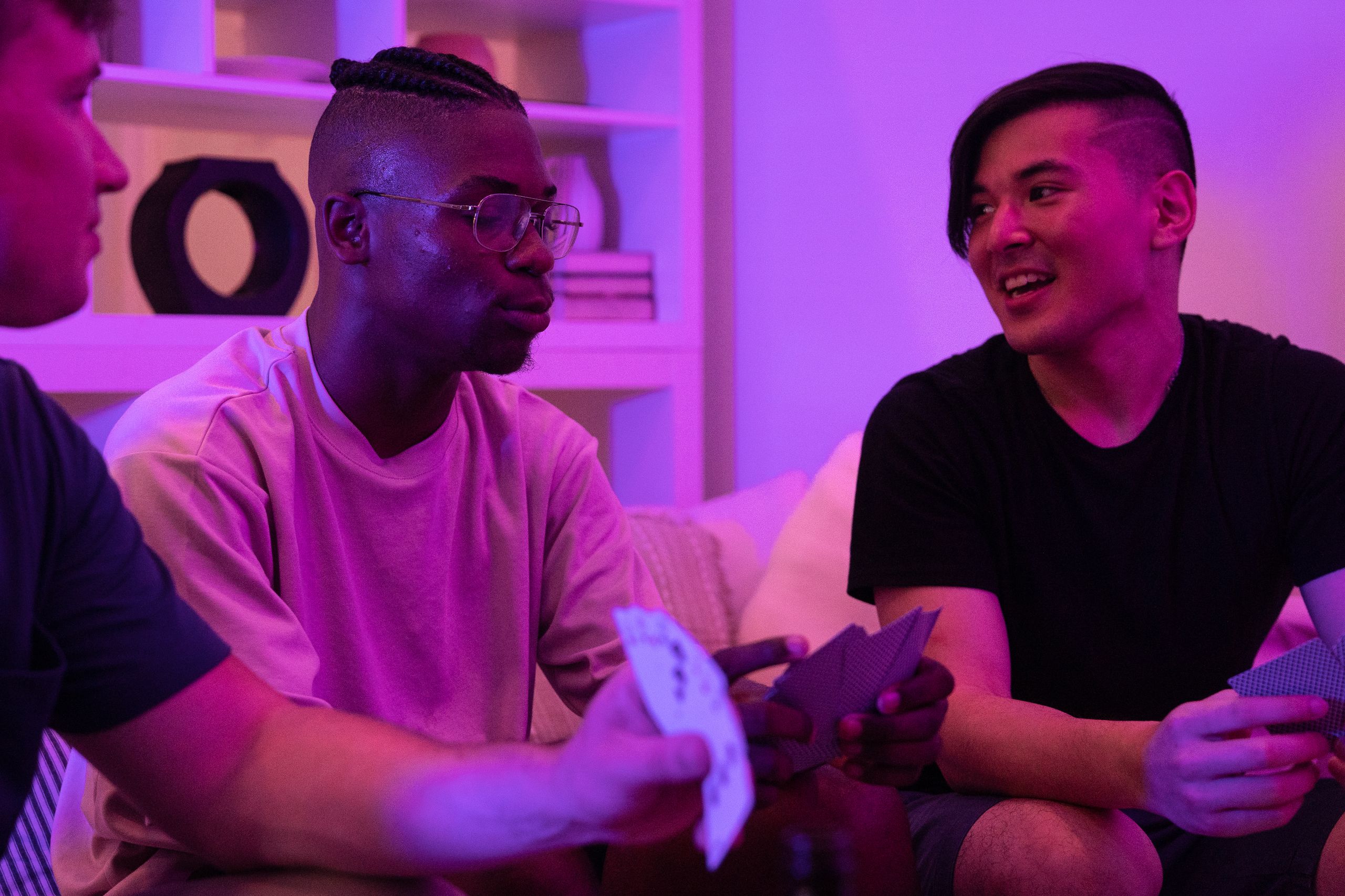 A group of diverse friends playing cards and enjoying a fun night indoors with mood lighting.