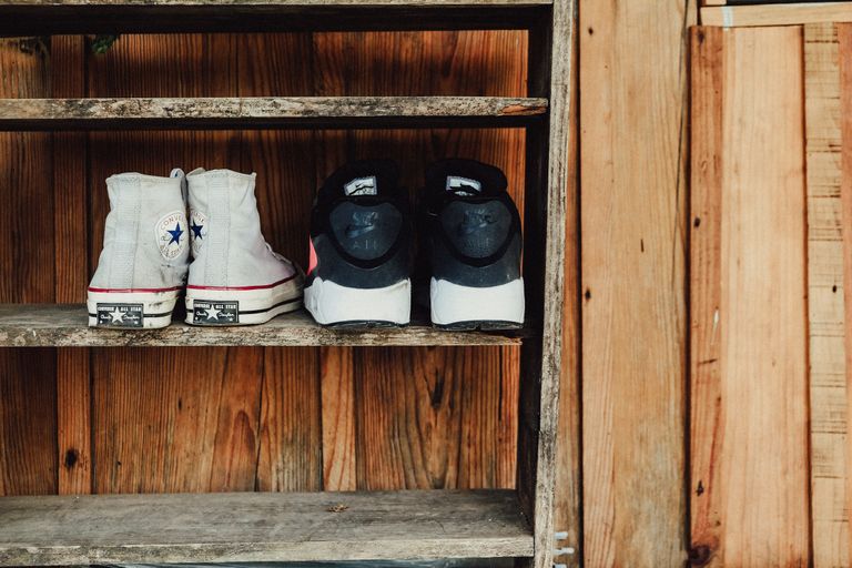 A rustic wooden shelf displaying Converse All Star and Nike shoes, perfect for fashion and vintage themes.