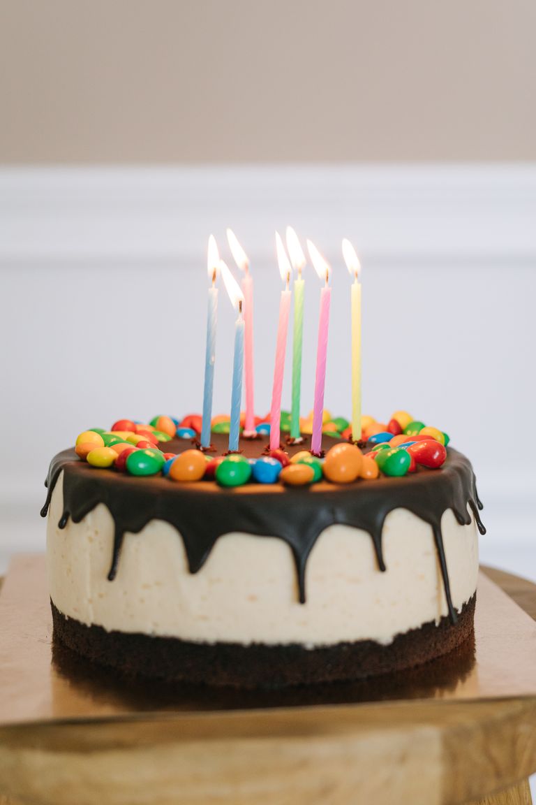 A vibrant birthday cake adorned with colorful candies and lit candles.
