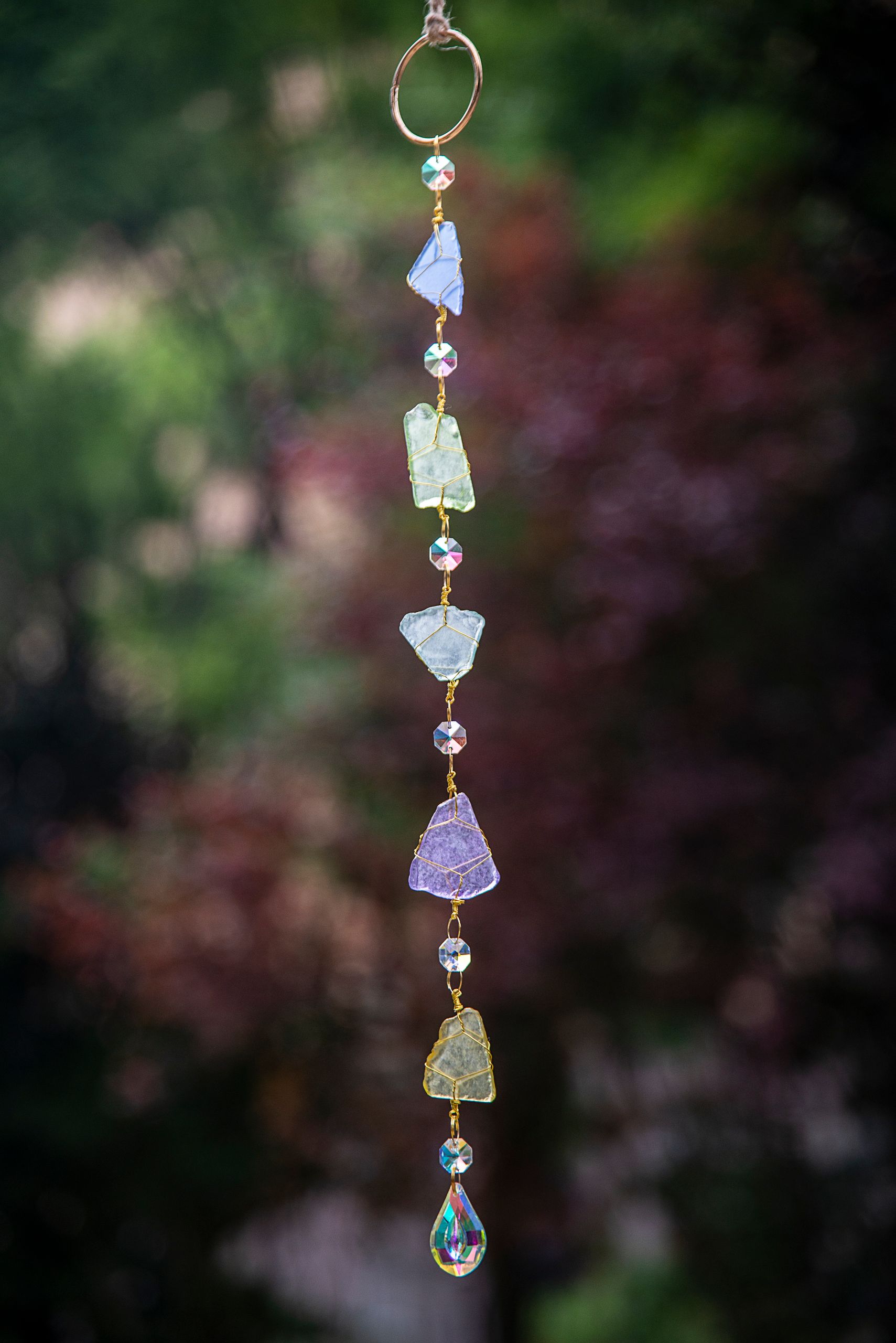 A vibrant hanging crystal suncatcher against a soft, natural out-of-focus background.