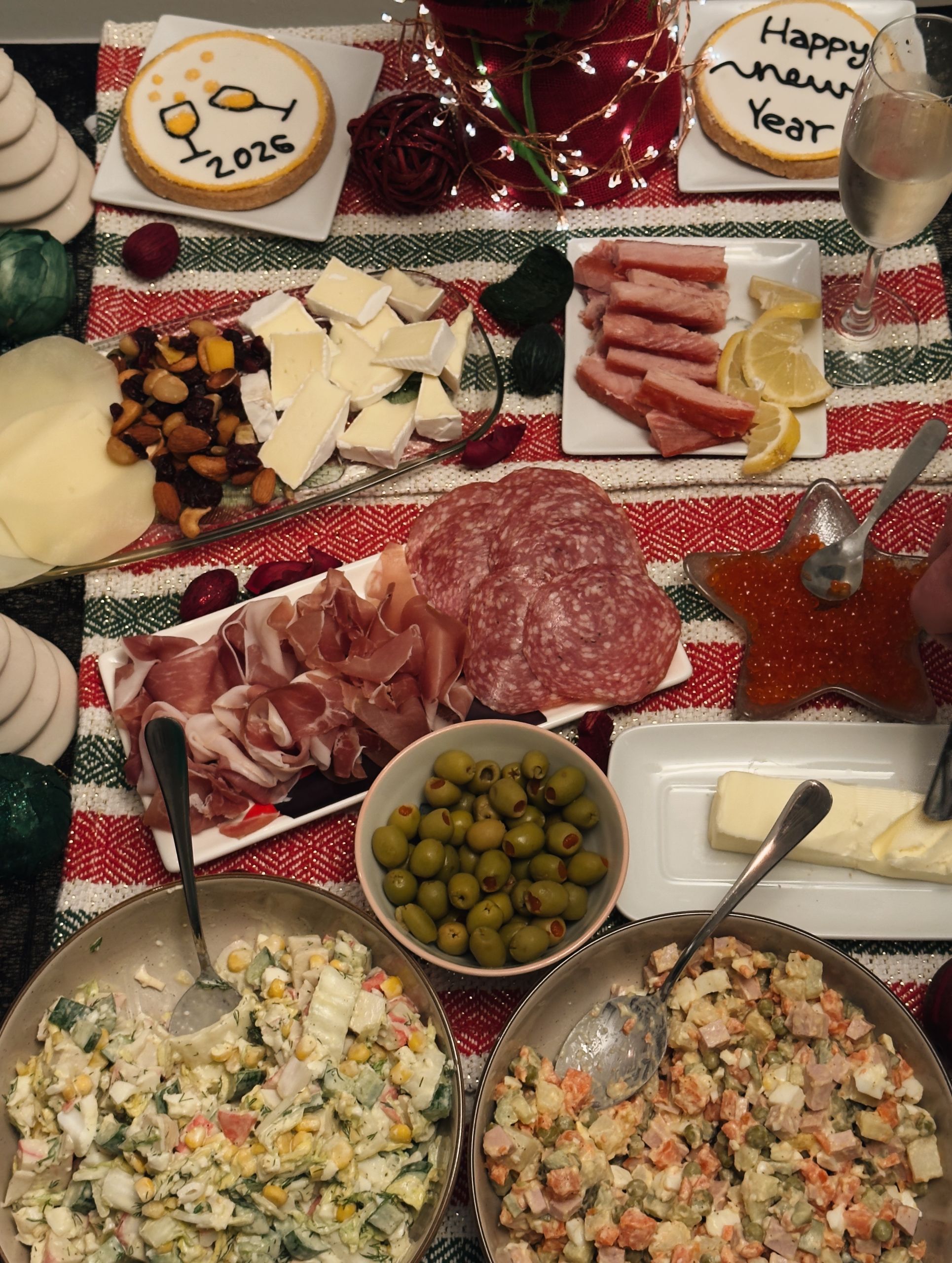 A vibrant New Year feast with salads, meats, cheeses, and festive cookies marked with 2024.
