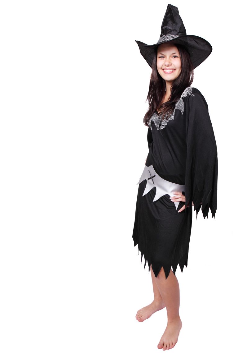 Cheerful woman in a black witch costume posing on a white background.