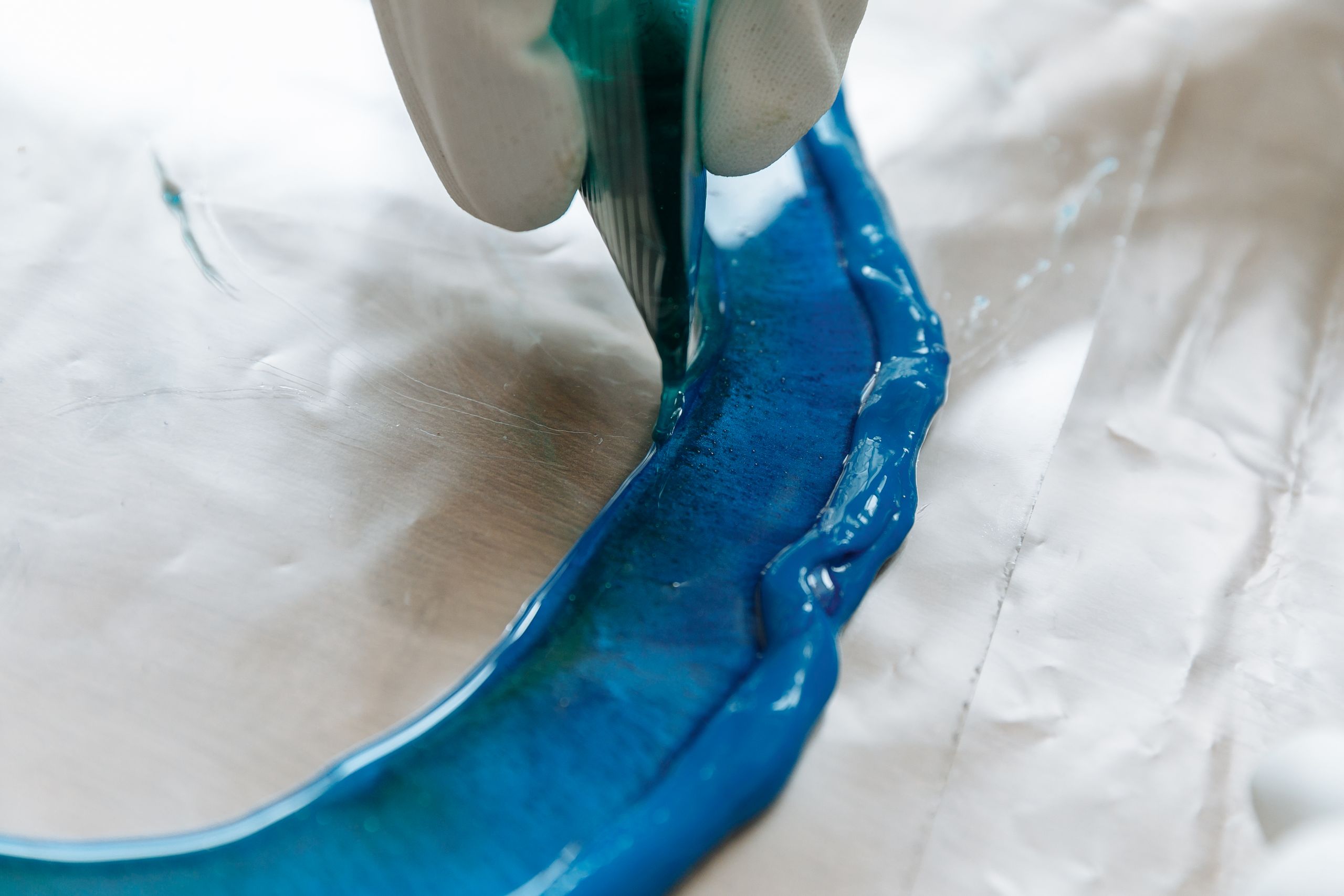 Detailed view of blue resin being poured in an art project, perfect for DIY crafts.