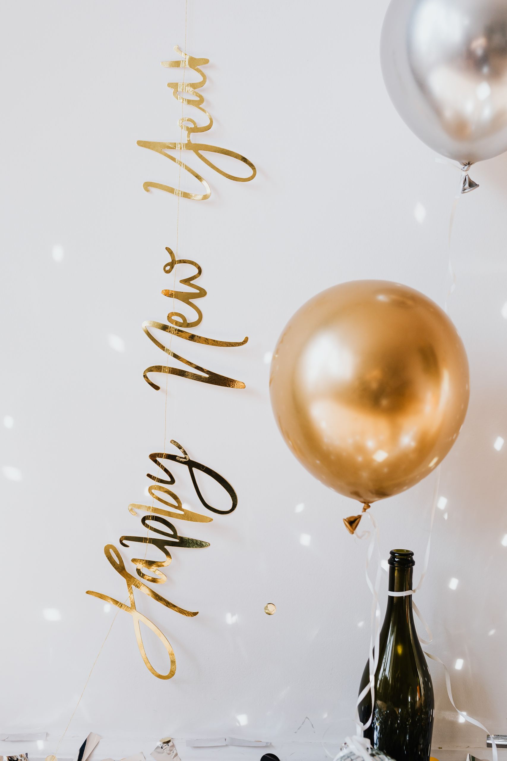 Elegant New Year's Eve setup with balloons, champagne, and festive lights.