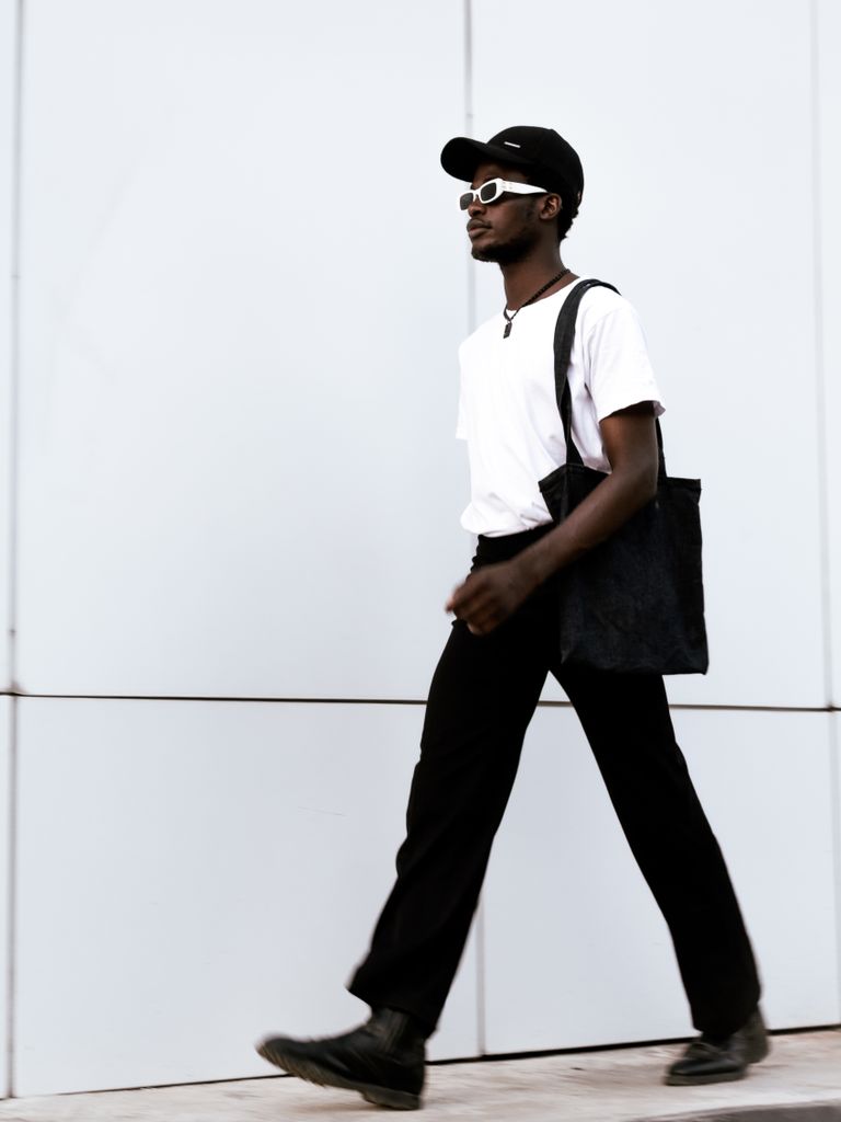 Fashionable adult walking with tote bag in urban setting, showcasing casual style.