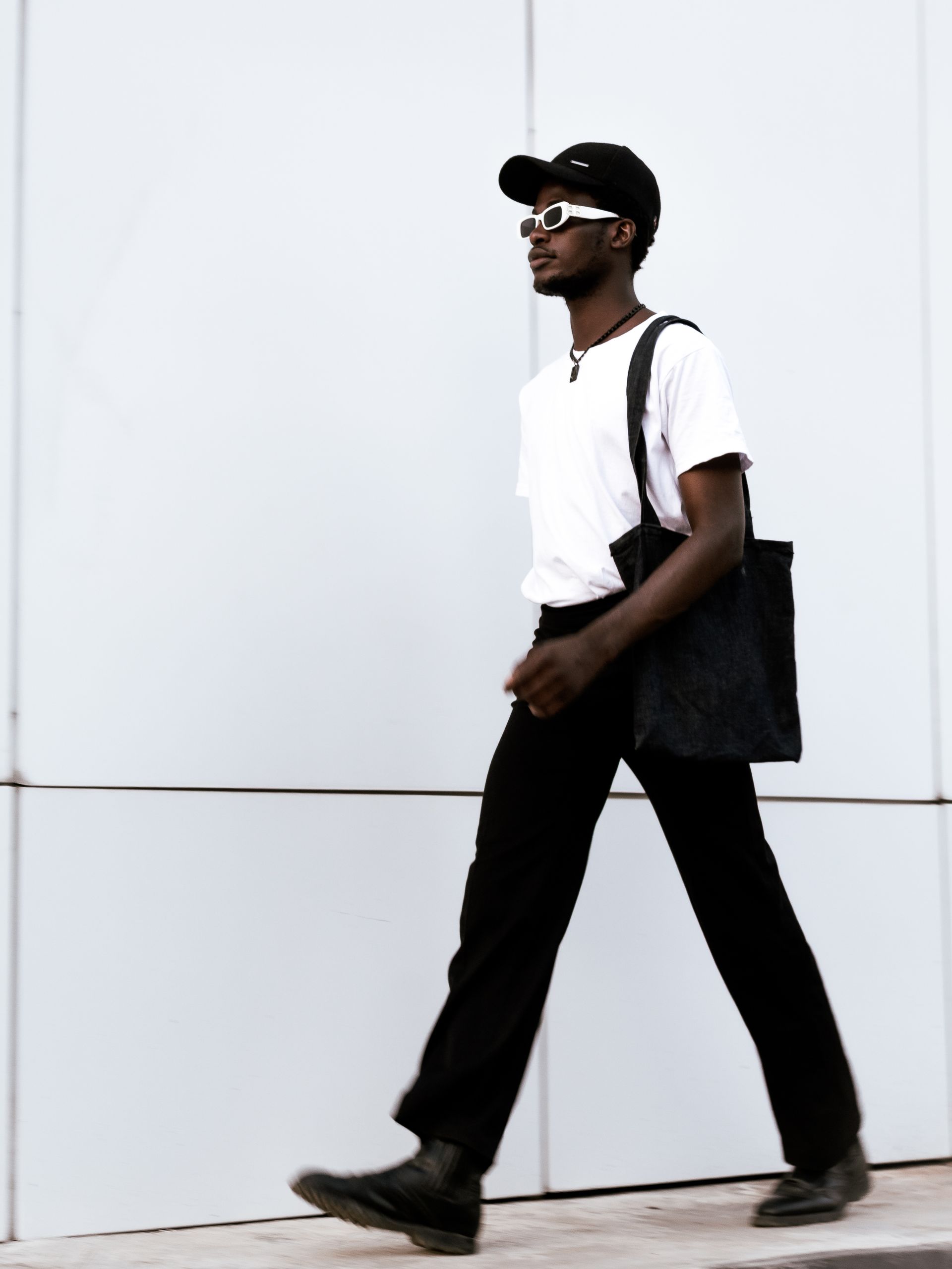 Fashionable adult walking with tote bag in urban setting, showcasing casual style.