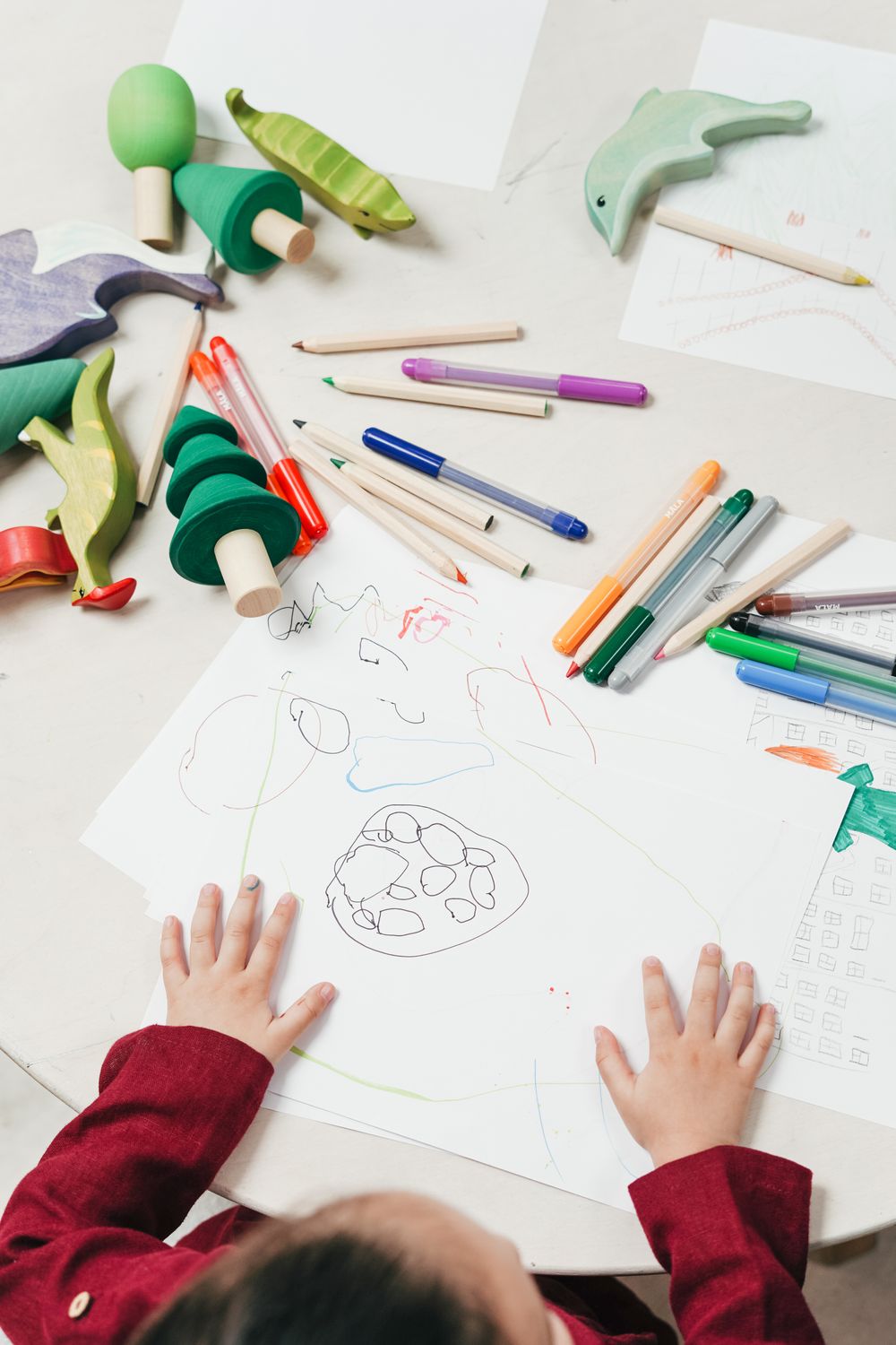 Child drawing with colored pencils at a table, ready to sketch a sleepy cat