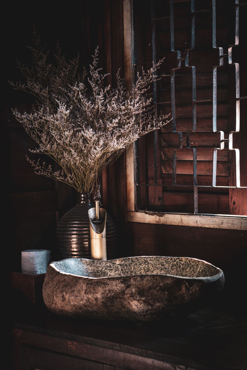 Natural stone basin and decorative vases in a rustic bathroom create an inviting and stylish ambiance. Stock Photo.