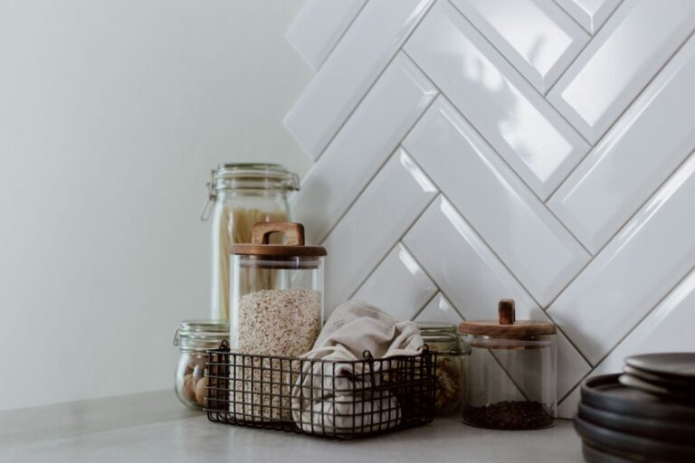 Stylish kitchen setup featuring glass jars with pasta and grains on a clean counter. Stock Photo.