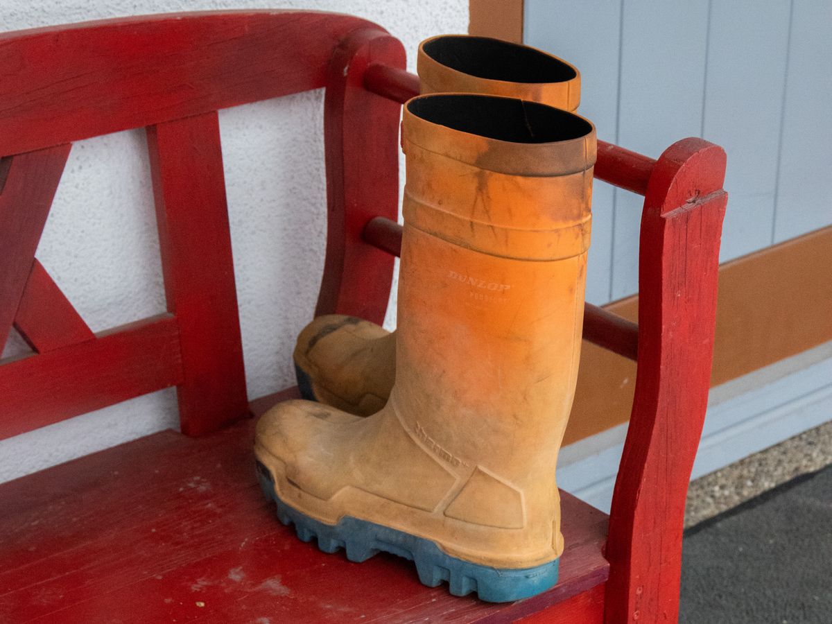 Orange rubber boots on a red entryway bench above a boot tray, one of my favorite boot storage ideas