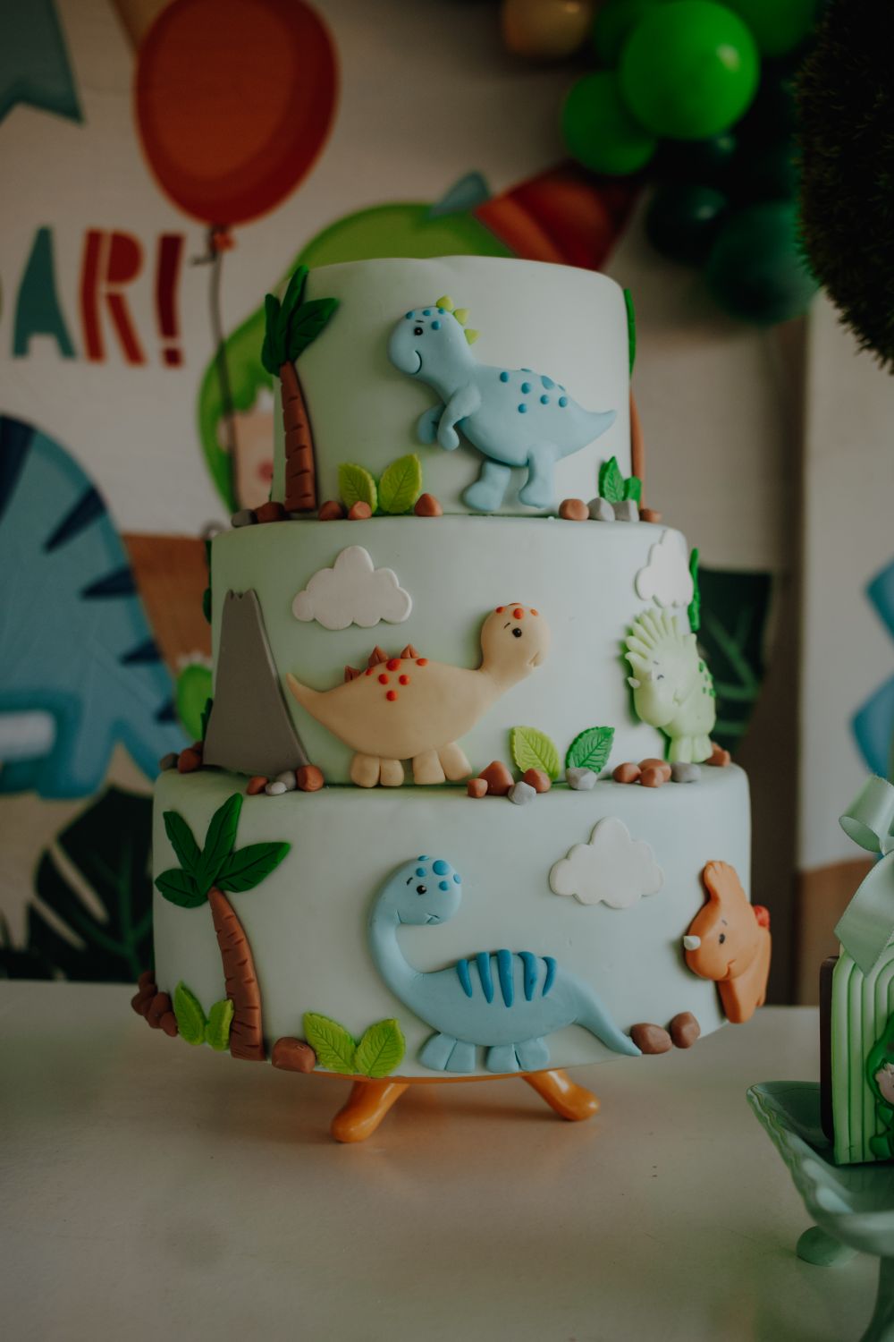Three-tier dinosaur-themed cake for a children's birthday party. Stock Photo.