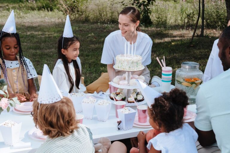 Children enjoying a lively outdoor birthday party with cake and decorations. Stock Photo.