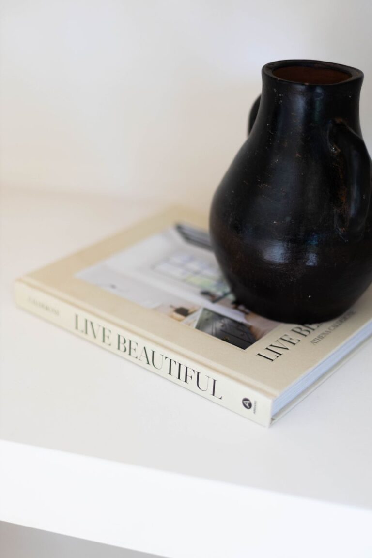 Simple black pottery on Live Beautiful book, embodying elegance. Stock Photo.