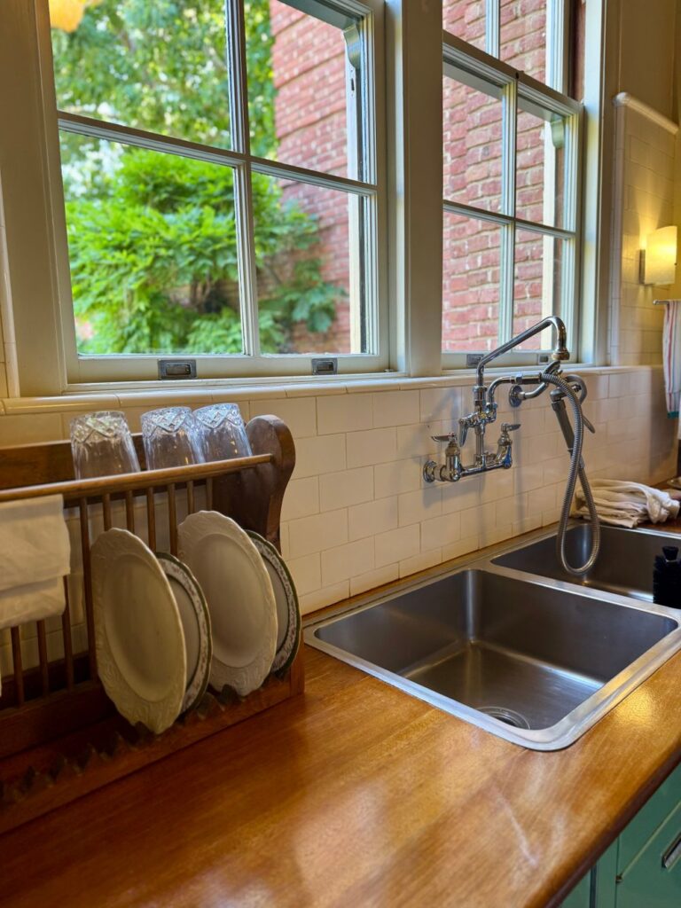 A traditional kitchen sink area with plates, faucet, and window view. Stock Photo.