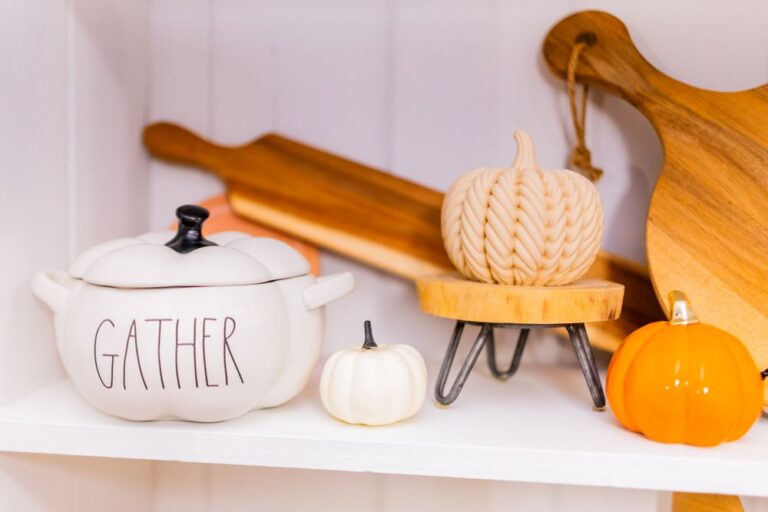 Warm and inviting autumn-themed kitchen decor featuring pumpkins and a 'Gather' pot. Stock Photo.