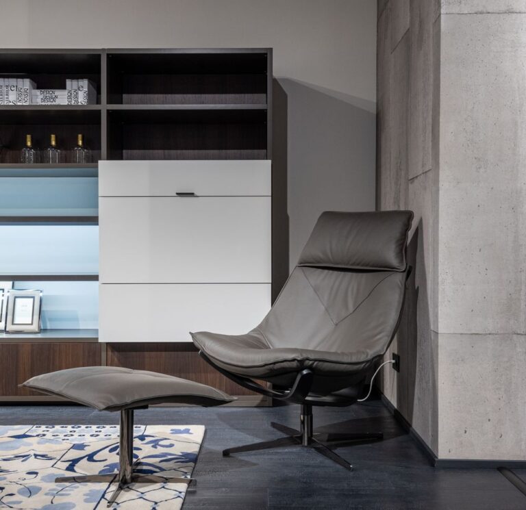 Leather chair with a footrest beside a cabinet with shelves in a modern living room