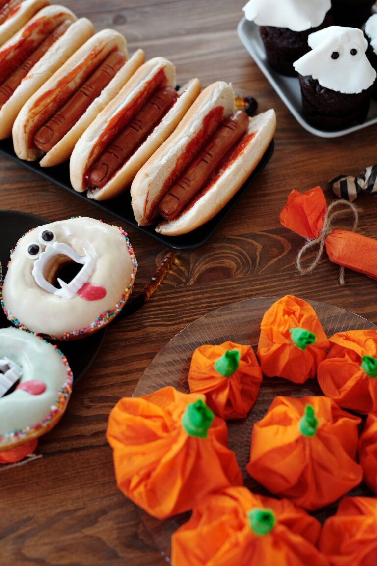 Halloween party snack board with mummy hot dogs, ghost cupcakes and pumpkin treats