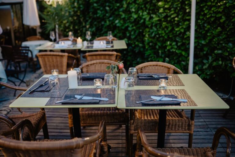 Intimate outdoor dining setting with wicker chairs and candlelit tables on a charming terrace. Stock Photo.