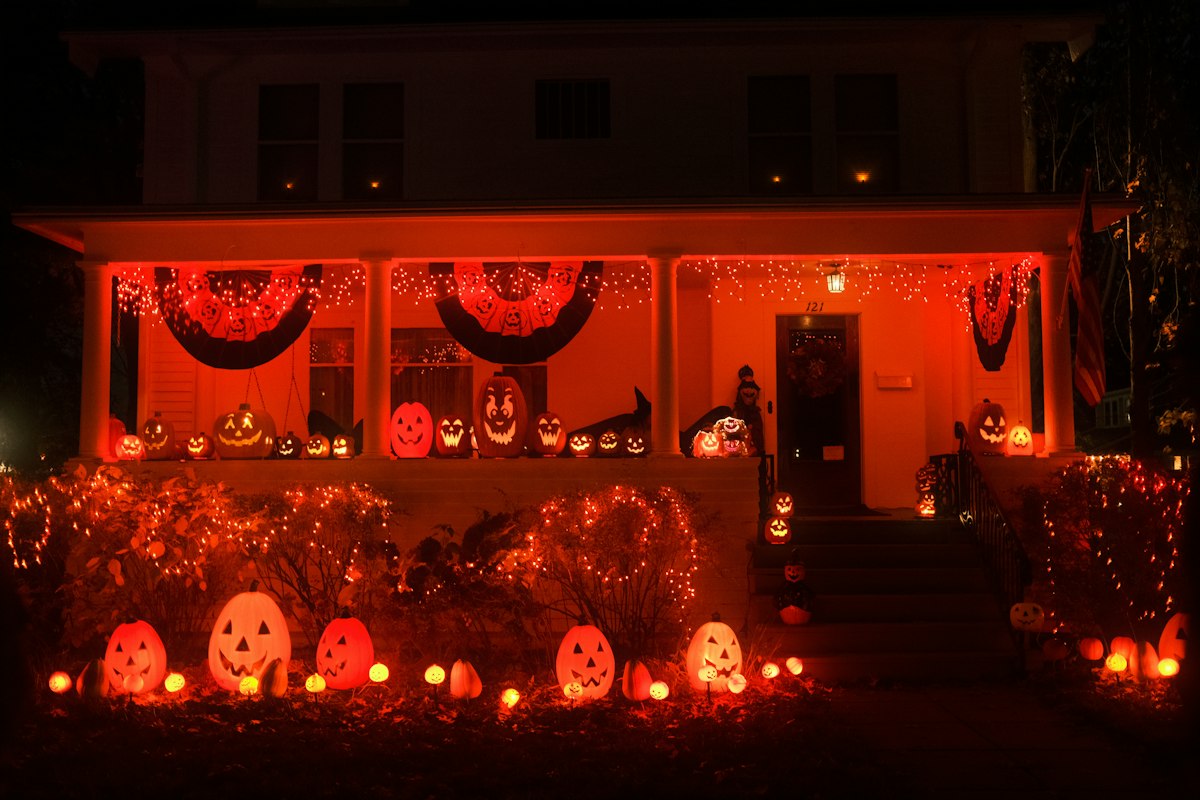 Spooky Halloween porch decorated with glowing pumpkins and orange lights