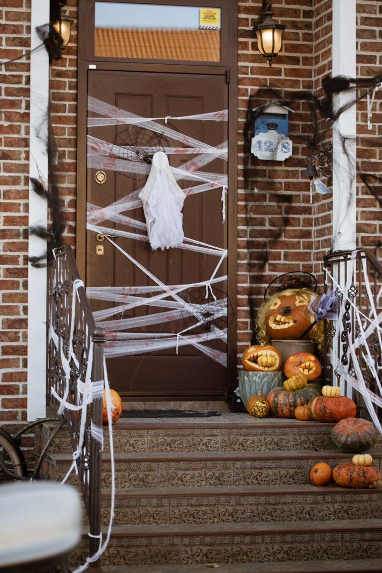 Front door decorated for Halloween with pumpkins and ghost, creating a spooky entrance.