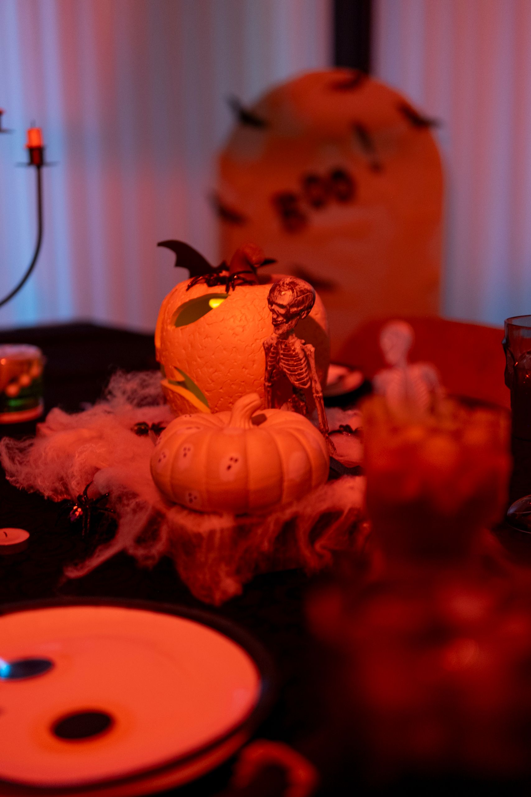 Halloween-themed table with carved pumpkins, skeleton, and spider web decor set for a spooky celebration.