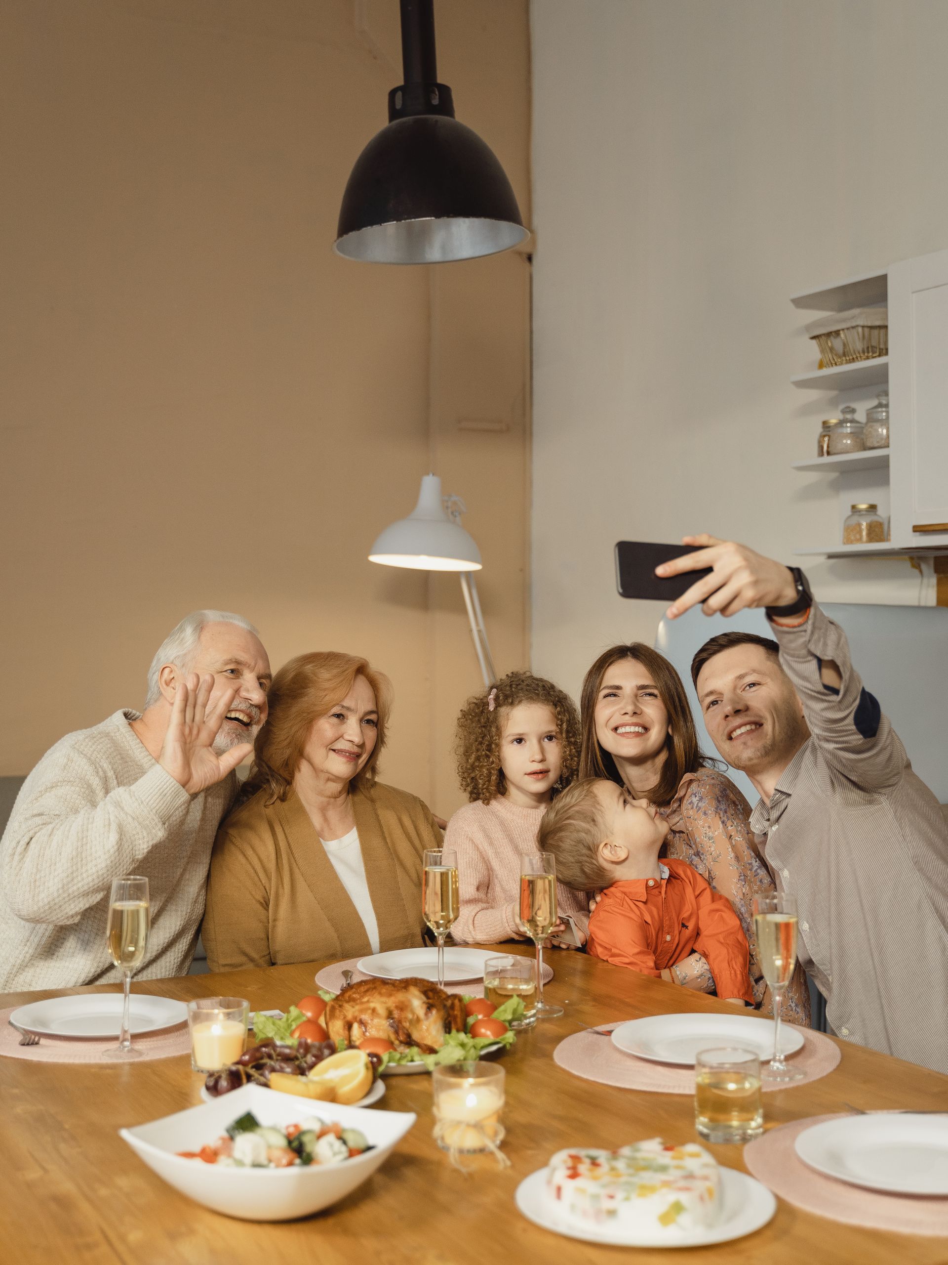 Happy family taking a selfie during a festive dinner gathering at home, capturing joyful moments together.