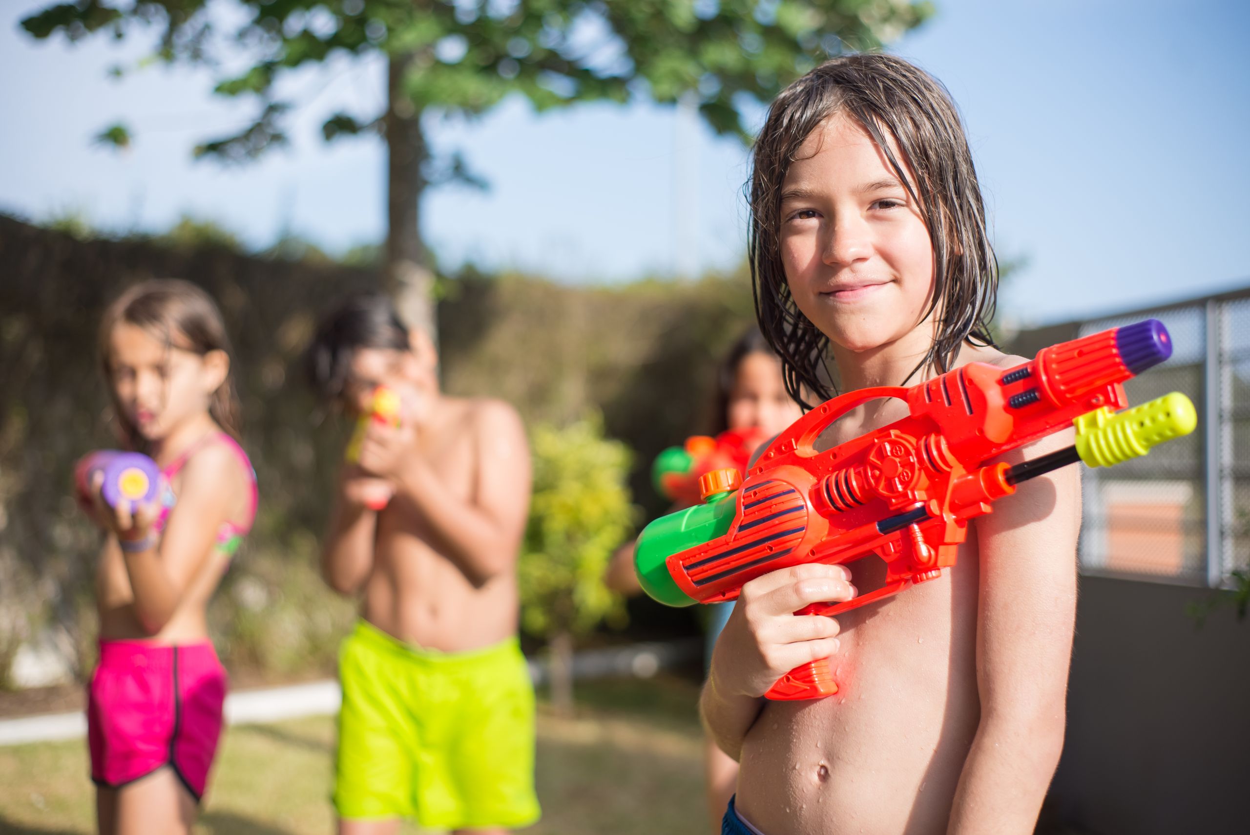 Kids enjoying a fun water gun fight outdoors on a sunny summer day. Bright and playful scene.