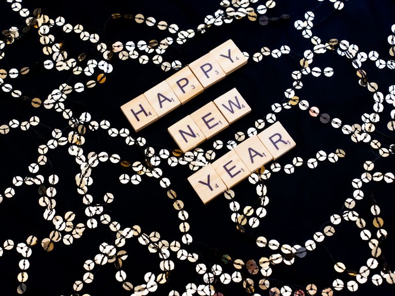 Scrabble tiles spell out 'Happy New Year' with festive decorations in Paris, France.