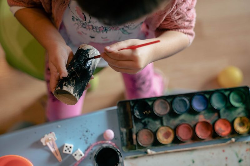 Child painting a cardboard roll with watercolors, toilet roll crafts for kids