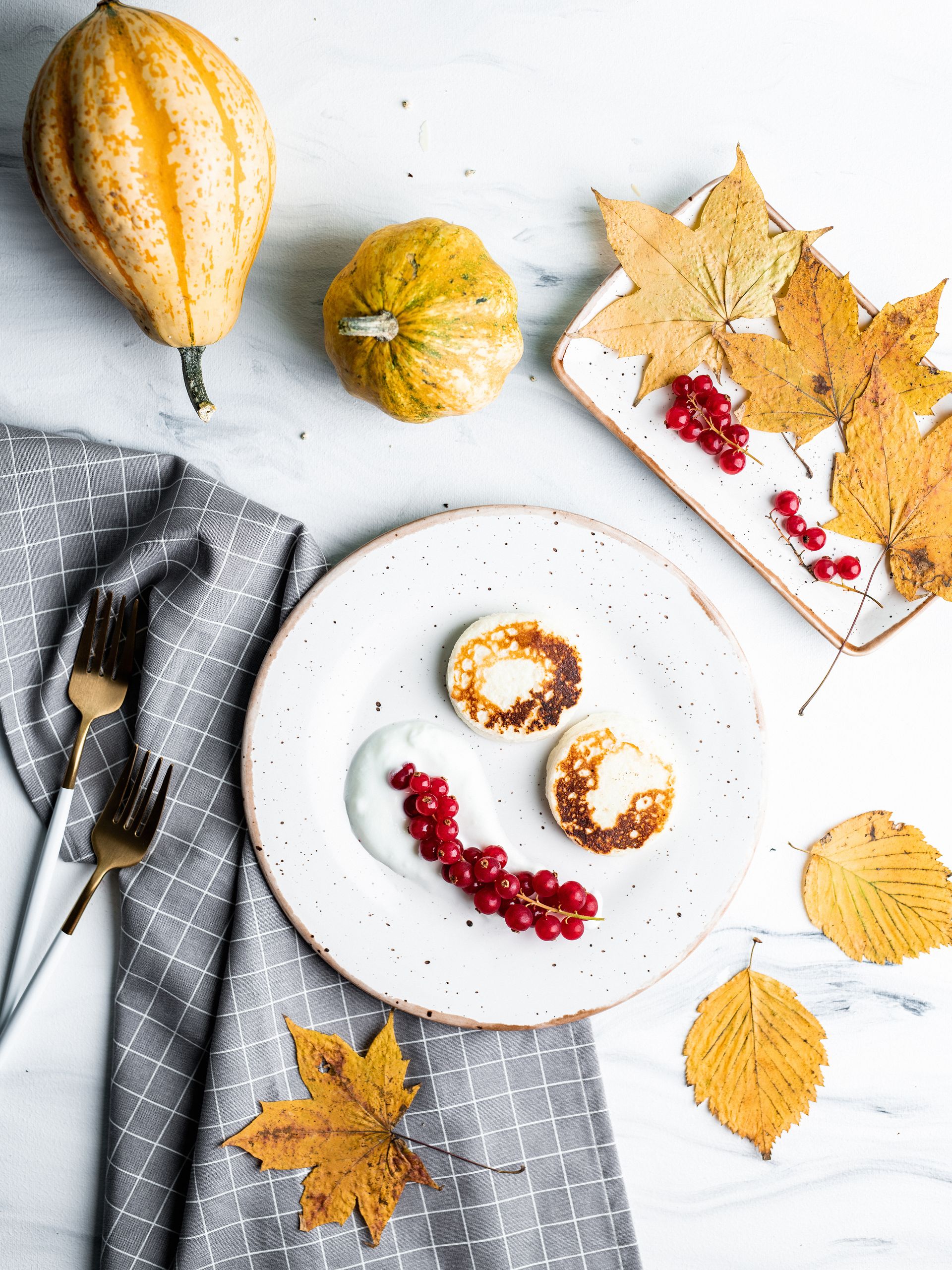 Top view of pancakes with berries, leaves, and pumpkins, capturing autumn vibes.