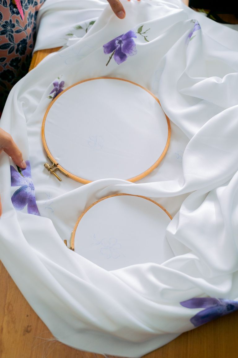 Two embroidery hoops placed on white fabric featuring purple floral designs, perfect for crafting inspiration.