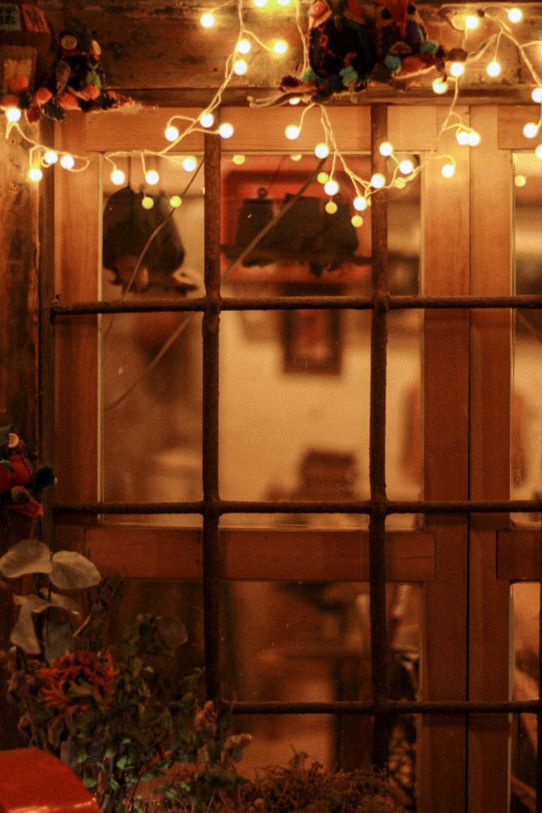 Warm evening scene of a window adorned with glowing fairy lights, creating a cozy atmosphere.