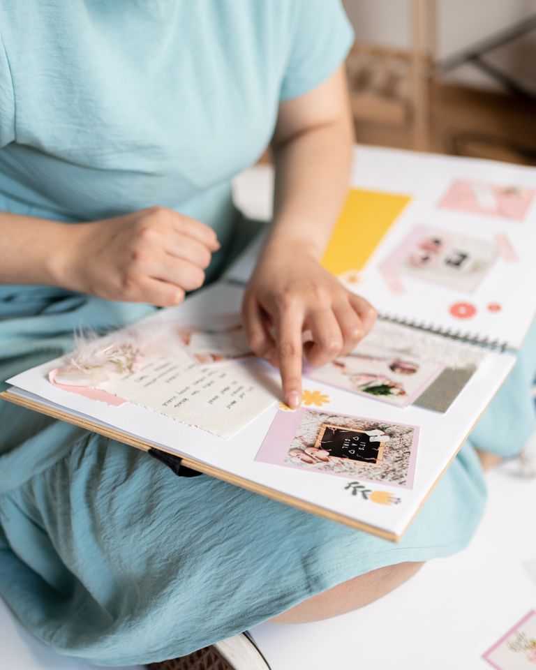 Woman engaged in scrapbooking, crafting a personalized photo album indoors.